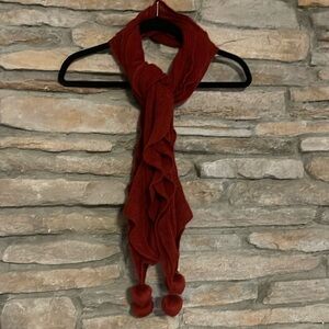 Red scarf with cascading ruffles and Pom poms on the ends.